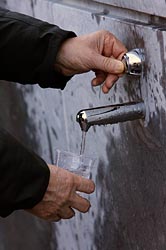 MAN FILLS GLASS WITH WATER FROM SPRING IN LOURDES