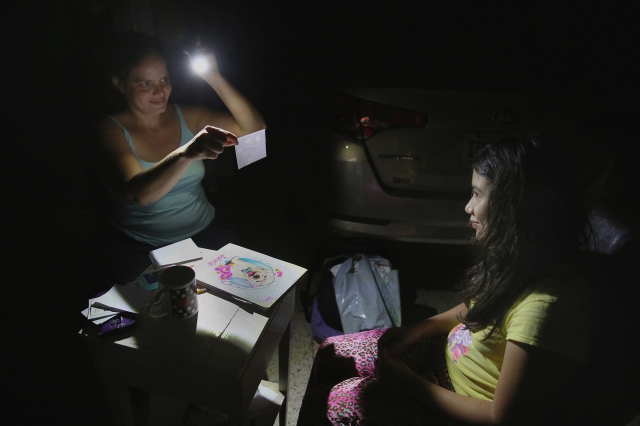 Margarita Rodriguez holds a flashlight as she quizzes her 11-year-old daughter, Isel Martinez, about homework outside their home in San Juan, Puerto Rico, Oct. 25. Most of Puerto Rico was without power and water for more than a month after Hurricane Maria devastated the island. (CNS/Bob Roller) 